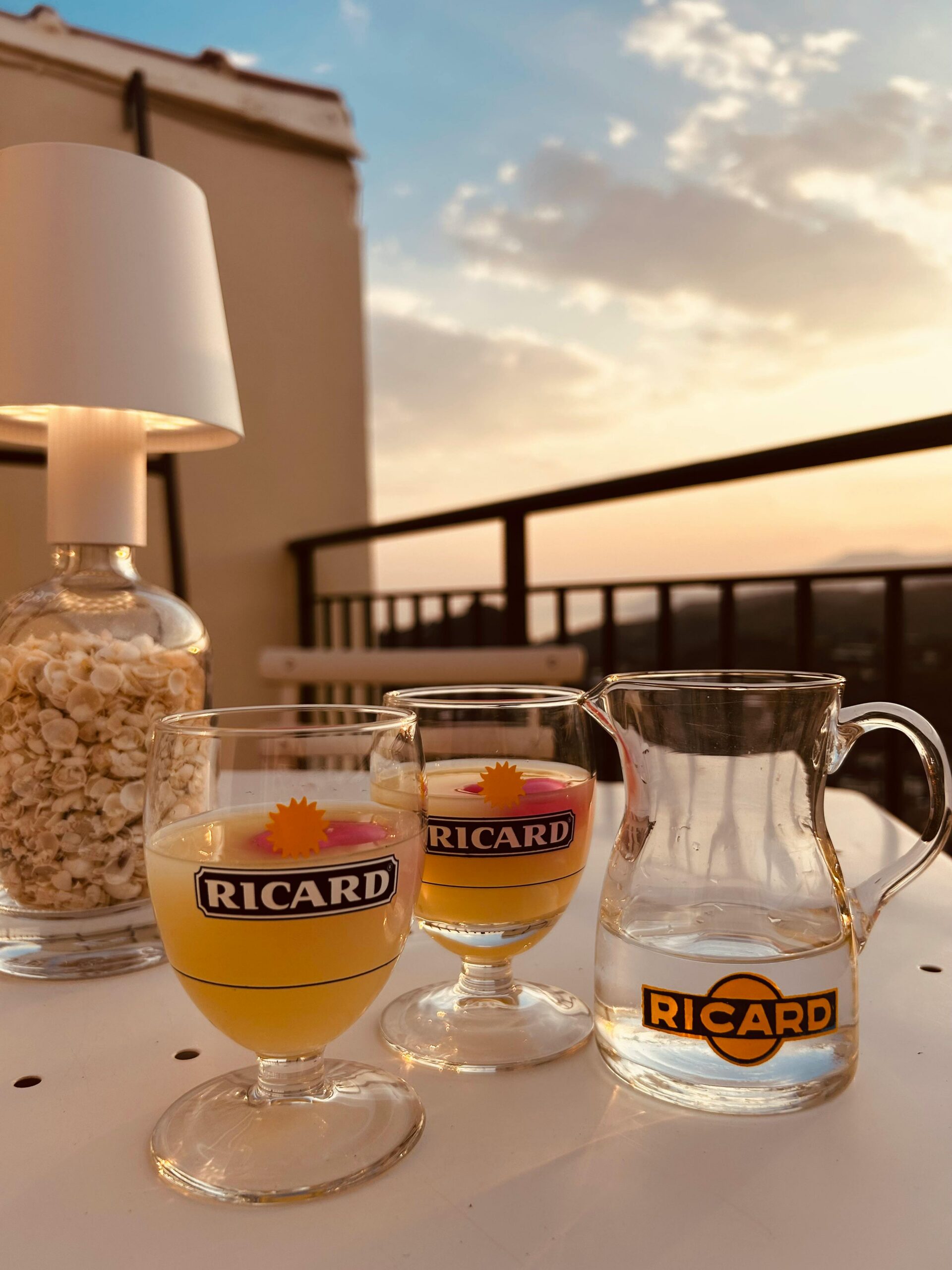 Cozy balcony setting with Ricard drinks and popcorn at sunset.